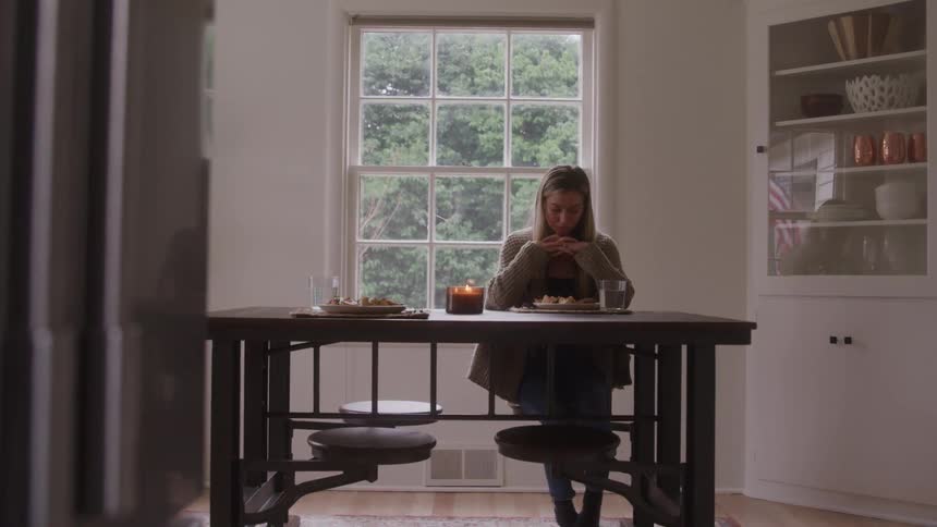 The woman is looking down at her food at home