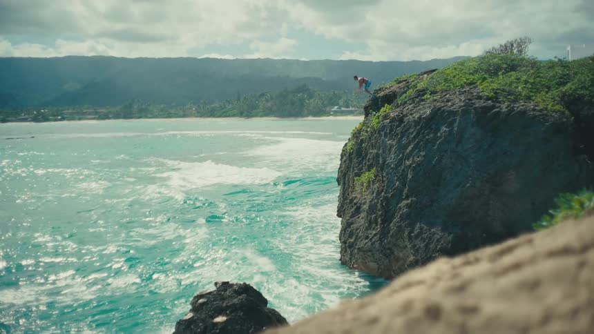 The man jumps off the cliff flipping into the water