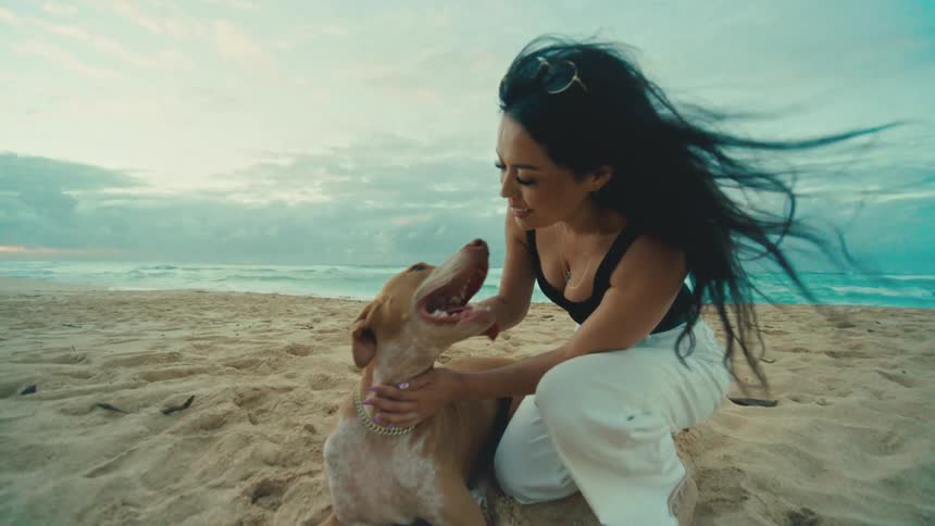 A woman gives her dog a kiss on the beach