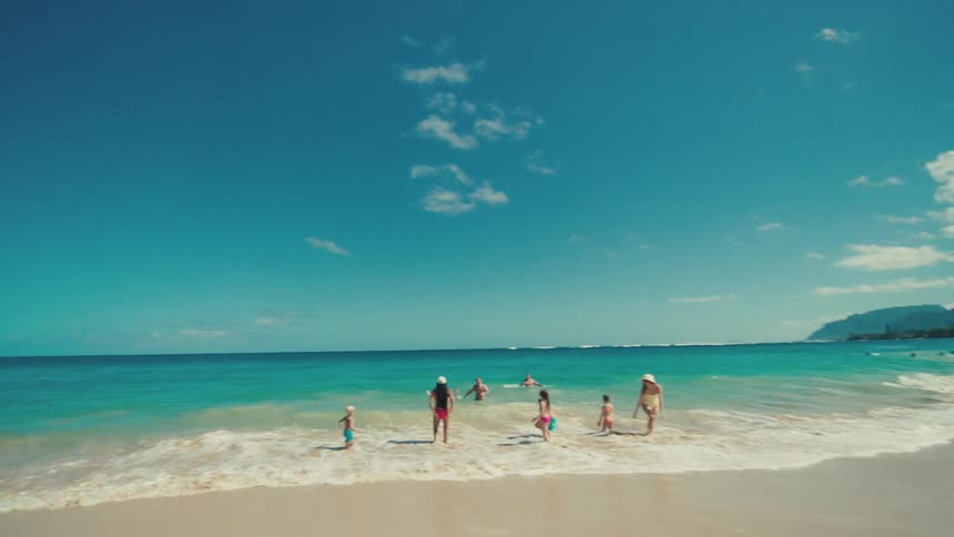 A group of people run into the blue waters on the beach