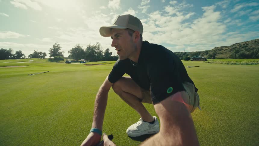 Man crouching and standing up while playing on an outdoor golf course