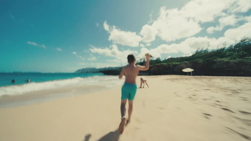 Children running barefoot on the beach on a summer day throw sand at each other