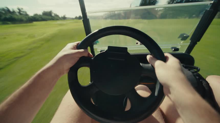 People are riding in the golf cart on the course