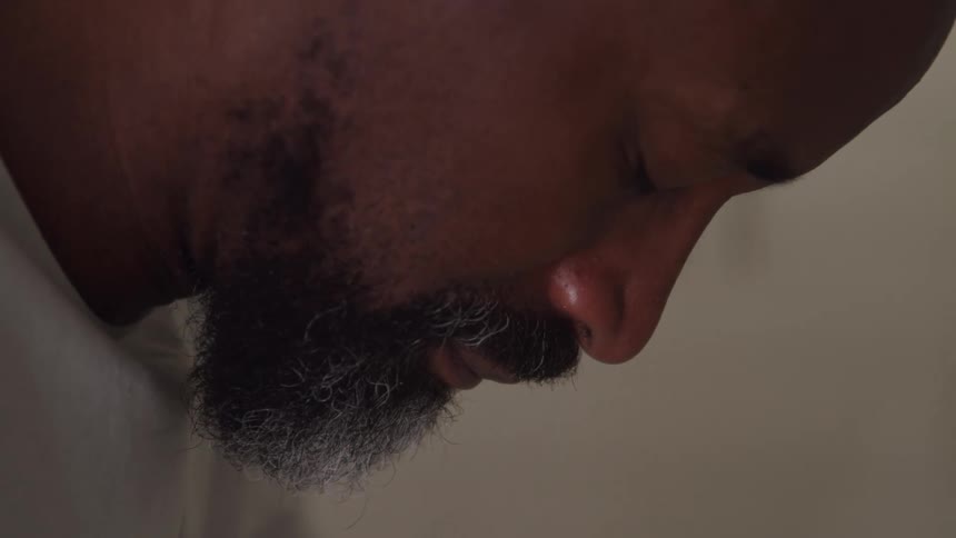 A sad looking man hangs his head down while closing his eyes