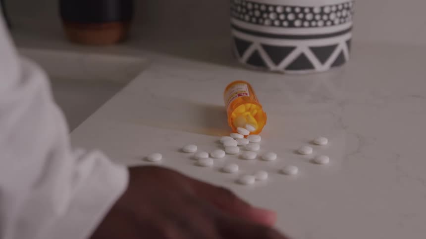 Pills from a medication bottle are spilled out on the counter