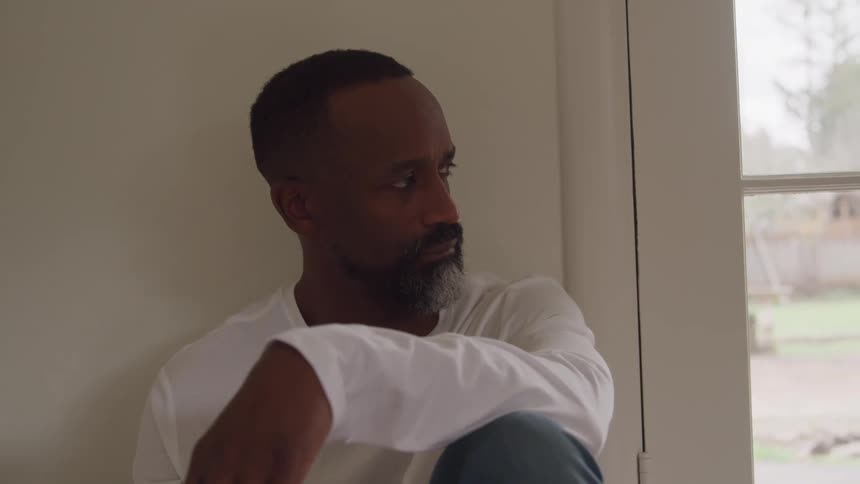 Man sitting indoors pensive looking to the side