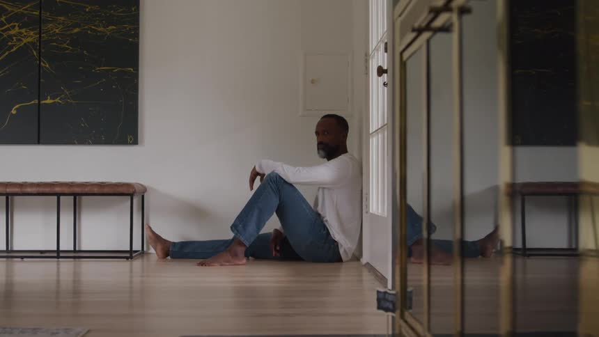 The man is sitting up against the door
