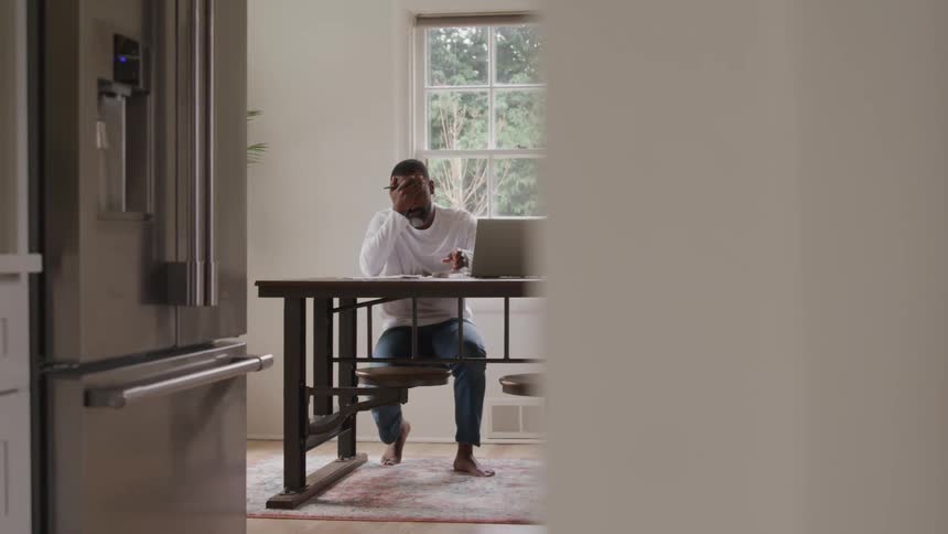 The man is holding his face by the laptop