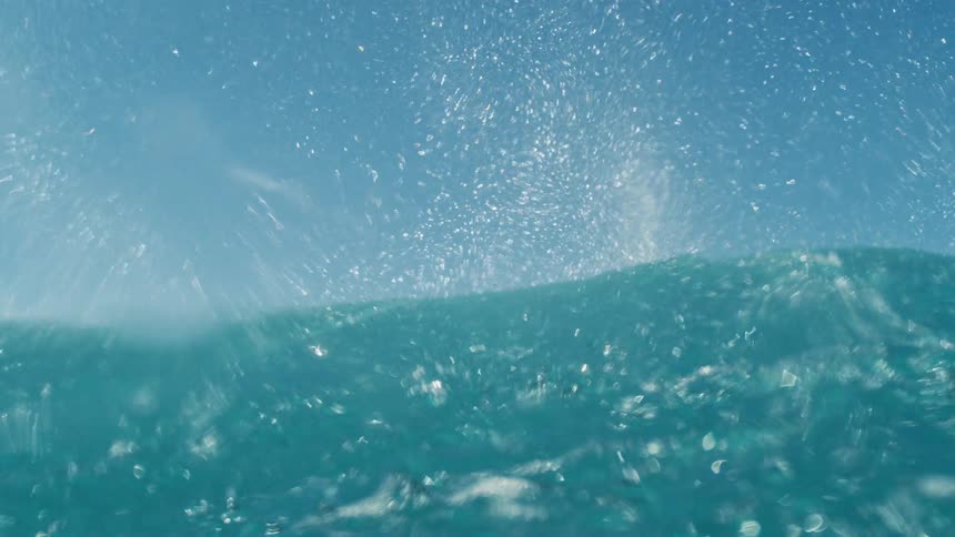 Blue wave crashing under a sunny sky