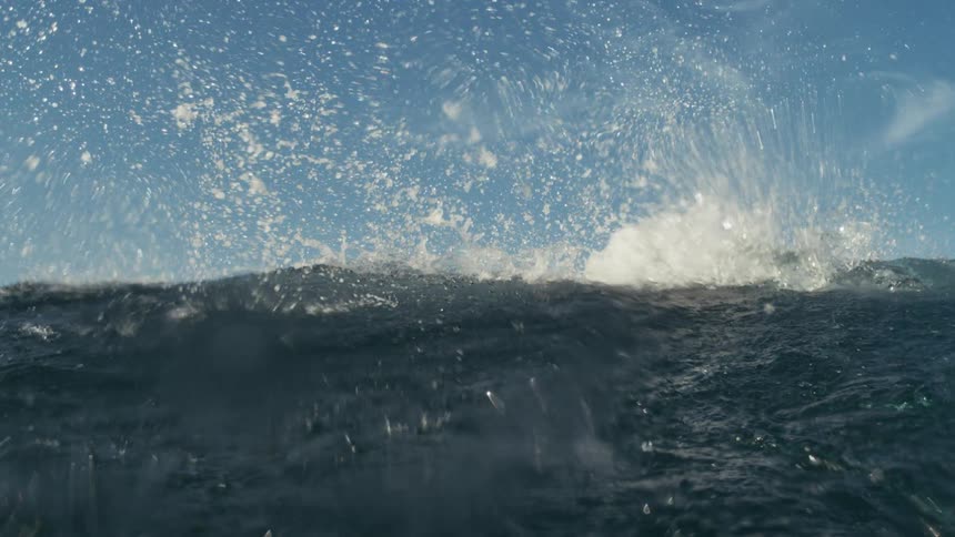 Crystal clear wave passing through the ocean during the day