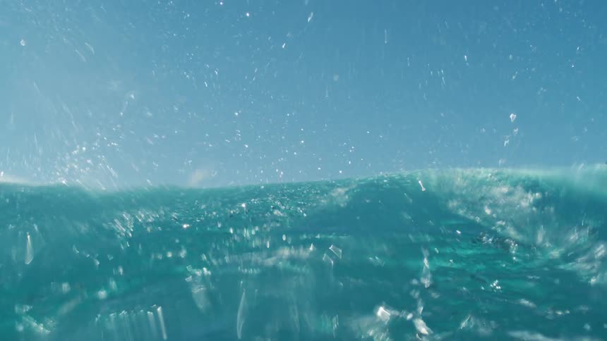 Crystal blue ocean with a wave passing by during the day