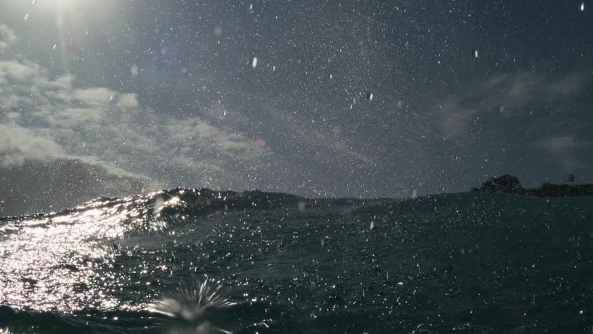 Waves crashing near the shore with water droplets suspended in the air