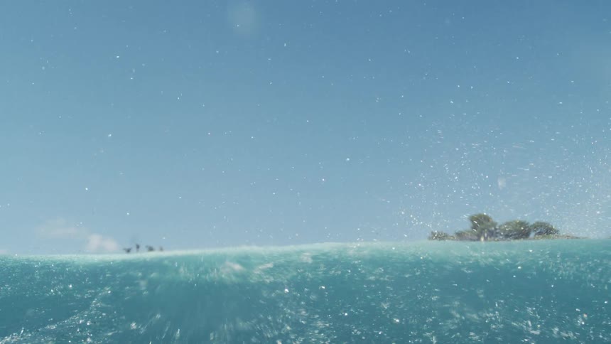 Waves roll against an island with houses on it