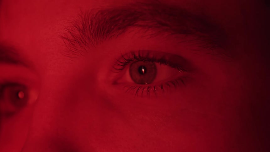 Eyes in closeup are lit by intense red light