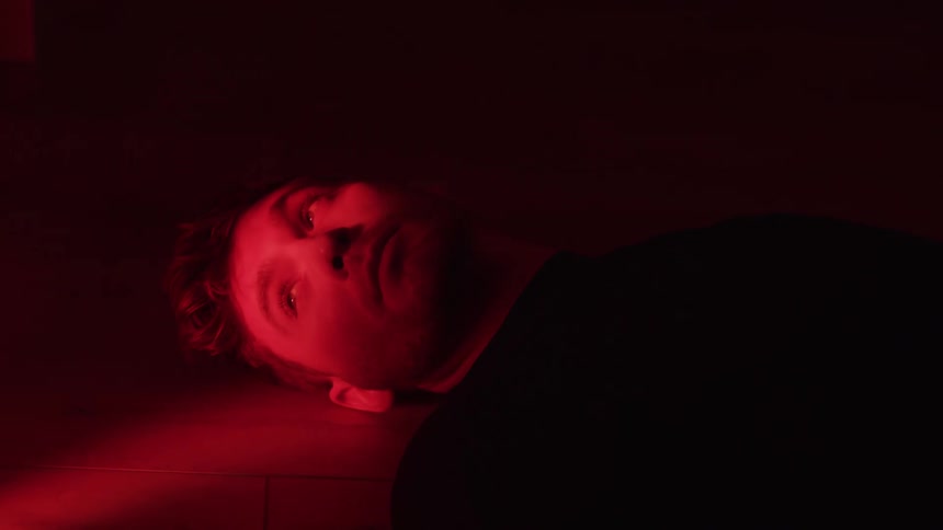 Man lying on the floor is bathed in intense red light