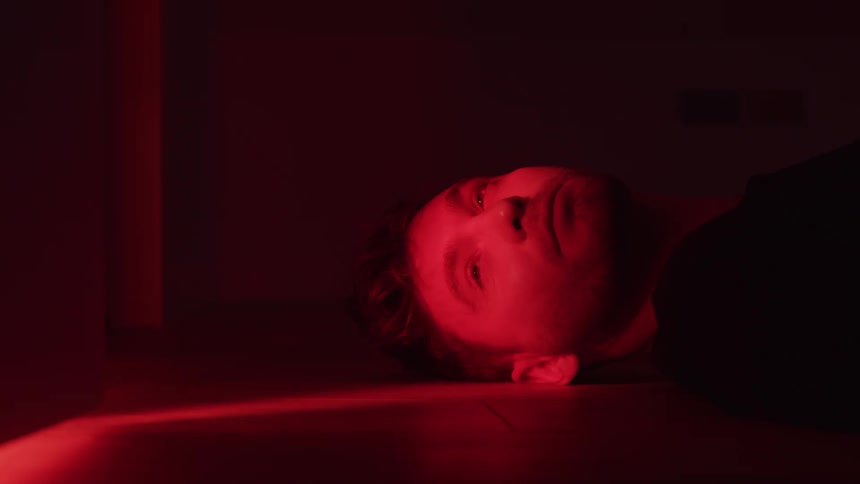 Man lying on the floor with a red light on his face