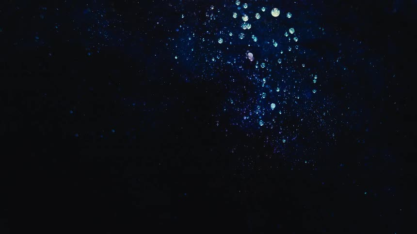 Bubbles float about in a darkness