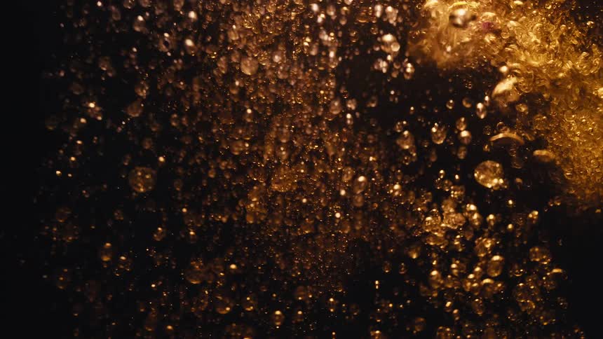 Golden bubbles rise in a dark liquid