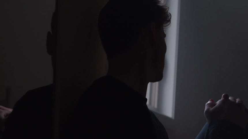 A man sitting indoor deep in thought and with sad expression on his face