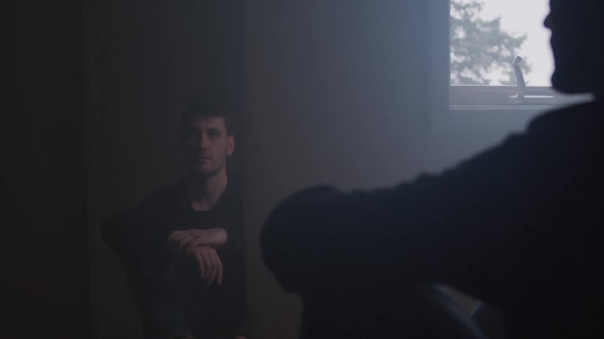 The man is sitting on the floor in front of a mirror