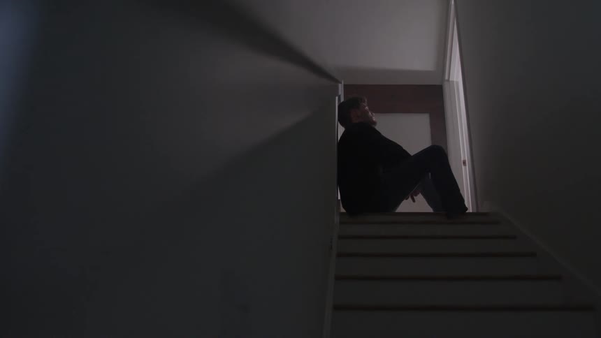 A man sits on a staircase in sadness and deep thought