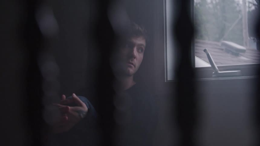 Man sitting near the window gazes outside with a distant expression