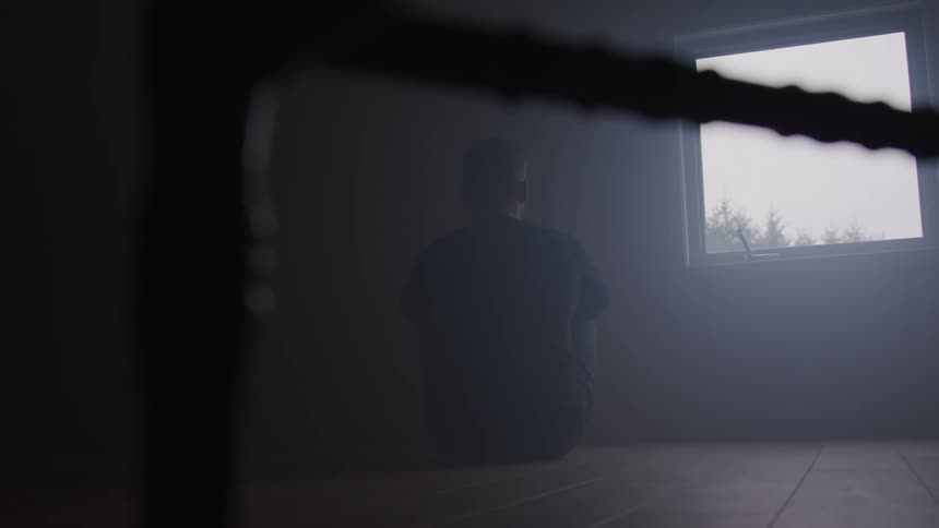 Man sitting on wooden floor looking out window