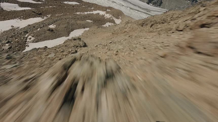 Aerial shot of a rugged mountain slope partially covered with patches of snow