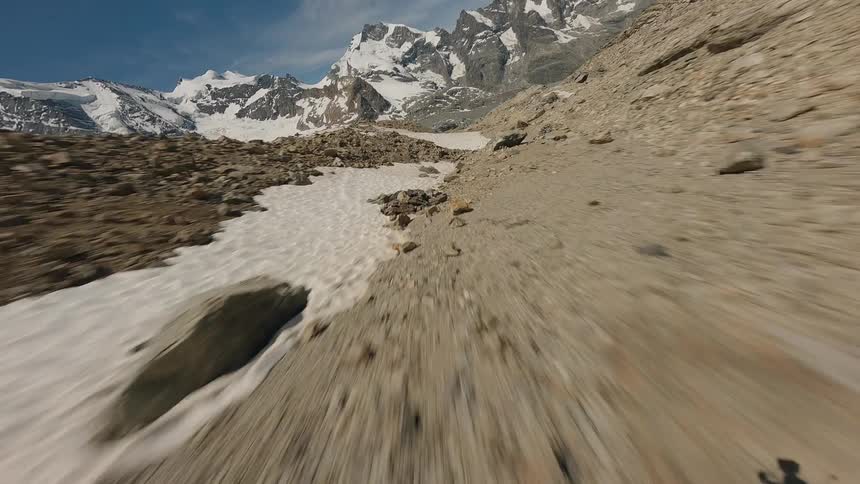 Aerial view of glacier between rugged peaks under clear blue sky