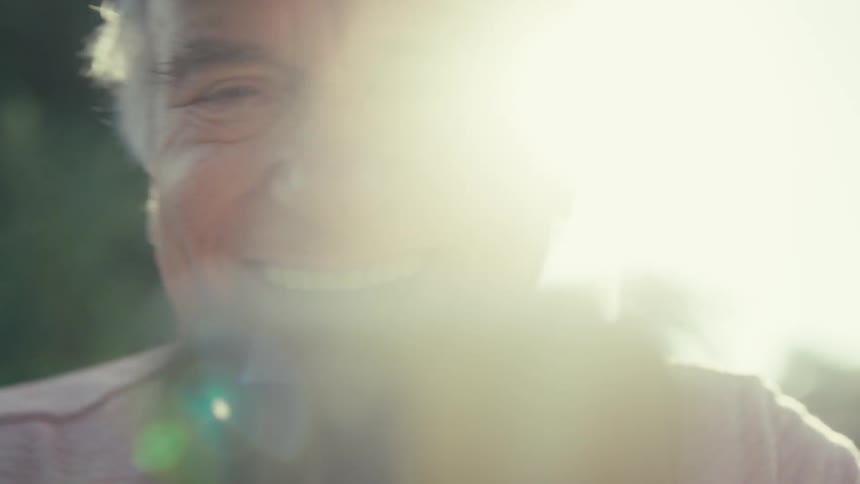 Elderly man happily video calling outside in a sunny neighborhood