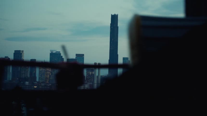 A city skyline at dawn features a series of highrise buildings and skyscrapers