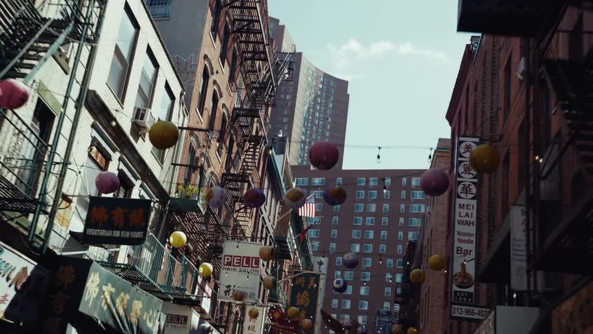 Spheres and electric lights hang on cables above a street passing between apartment buildings
