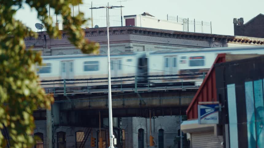 Public transit train travels along an elevated railway passing over a street near a post office