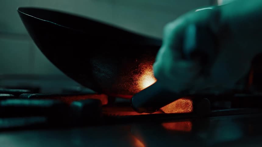 Hand with gloves holding an instrument and lighting a stove with a pan