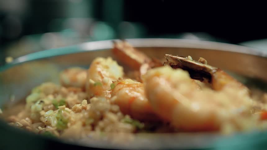 Seasoning being placed in a bowl with shrimp and rice