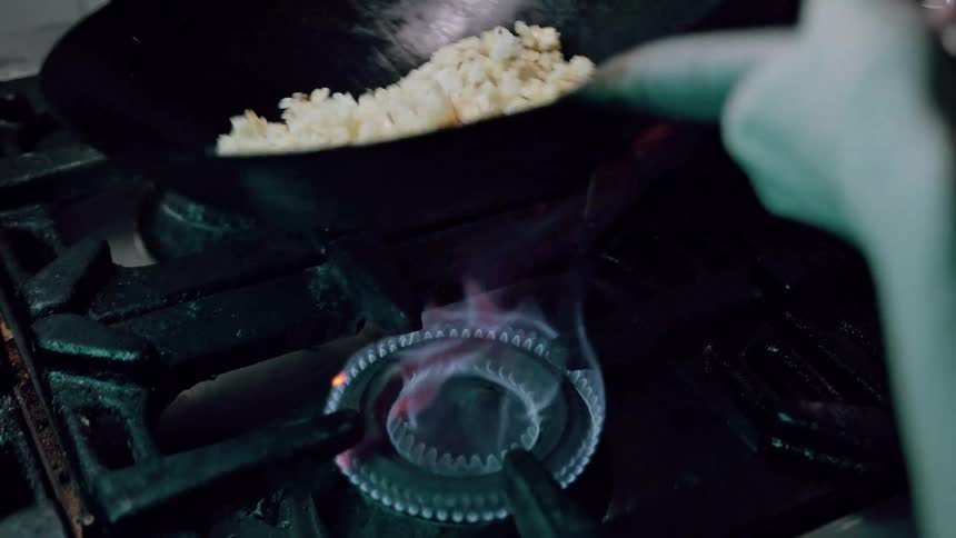 Chef tosses fried rice in modern kitchen