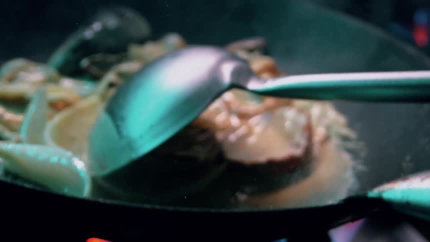Cook swirls seafood in a large skillet above a gas burner