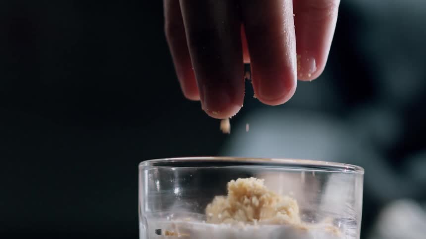 Sprinkling crumble topping on a dessert in a glass jar