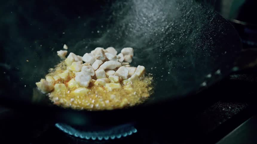 Meat is added to the mixture bubbling in a dark wok