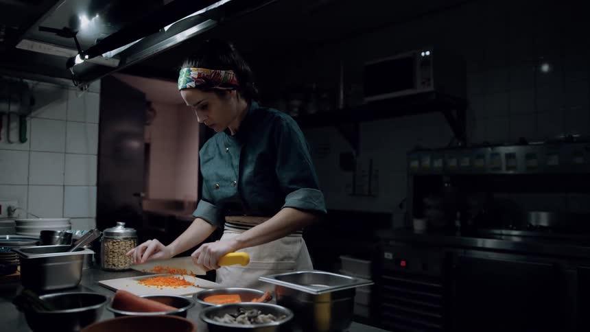 A chef is rolling and chopping food in a kitchen
