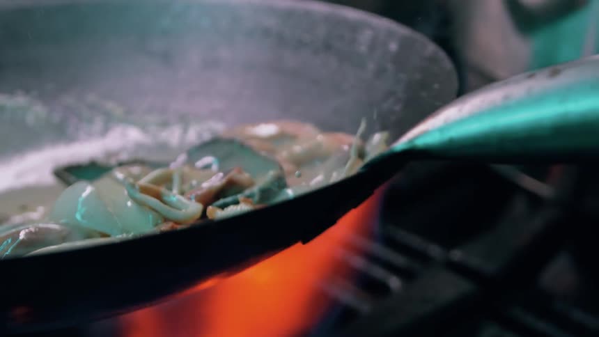 Steam rises off the cooking seafood in the wok
