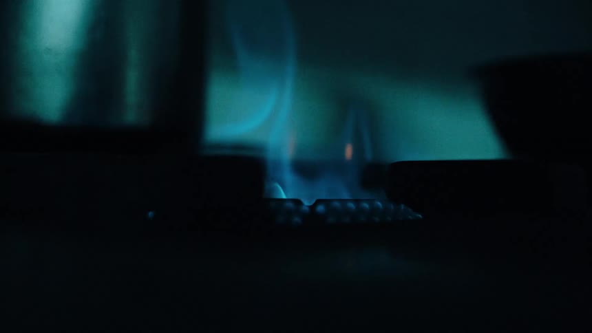 Close up igniting a gas burner with a long lighter