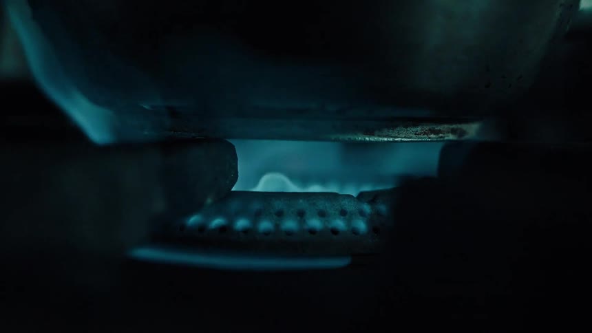 Flamesfrom a stove top burner lick over the base of a pot