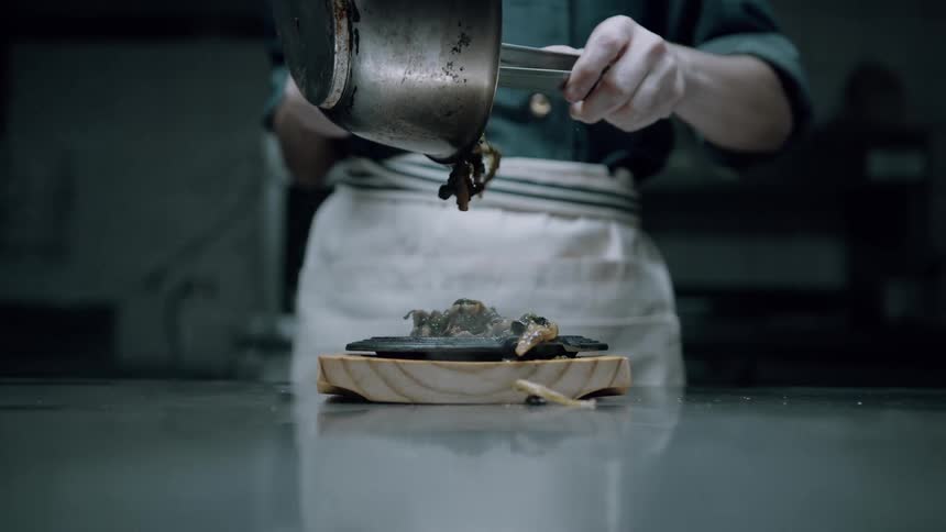 The chef pours food on the dish