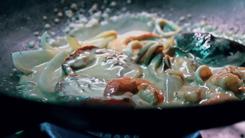 Sauteing a shrimp and muscle seafood meal in a saute pan