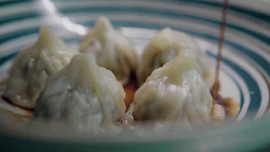 Sauce is poured over dumplings on a plate