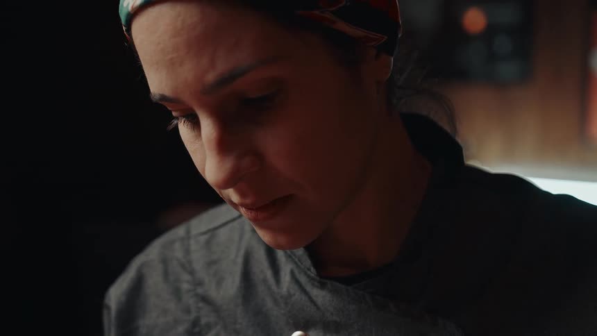 A chef cooks in the kitchen wearing a jacket and headband