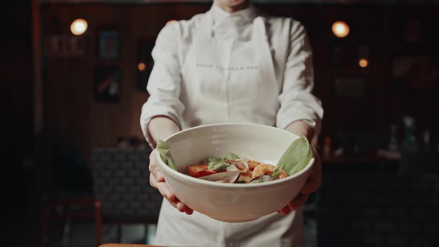 The woman holds out a bowl of food