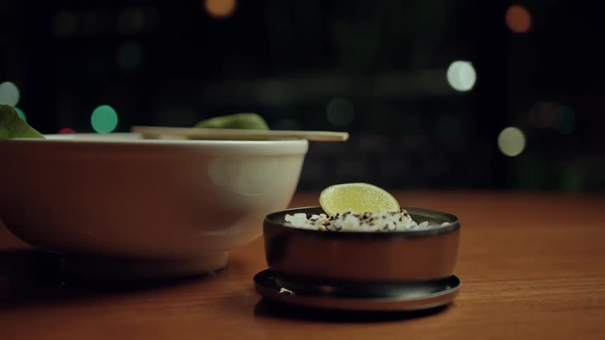 A plate and a bowl of food are served and placed on a wooden table indoors