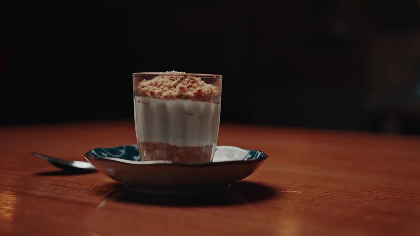 Custard dessert with crumbly topping in a glass jar in a small saucer